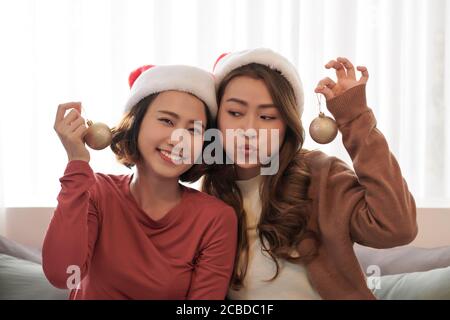 Deux mignonnes jeunes femmes dans le chapeau du père noël posant émotionnellement sur la séance photo du nouvel an. Banque D'Images