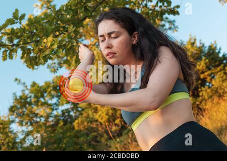 Jeune femme sportive tenant son coude, éprouvant de la douleur. Le concept des blessures sportives et de la médecine. Zone rouge. Gros plan. Banque D'Images