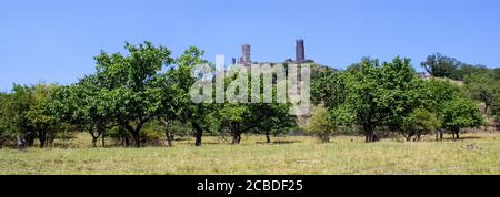 Ruines du château de Hazmburk au sommet du sommet de la montagne de ceske strodohori. Arbres fruitiers et ciel bleu. Banque D'Images