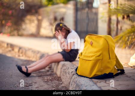 Élève malheureux avec sac à dos assis à l'extérieur. Fille qui ressent du stress. Enfants et émotions concept Banque D'Images