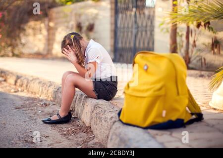 Élève malheureux avec sac à dos assis à l'extérieur. Fille qui ressent du stress. Enfants et émotions concept Banque D'Images