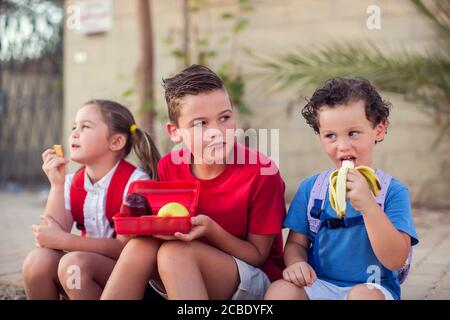 Enfants ayant une collation en plein air. Enfants, éducation et nutrition Banque D'Images