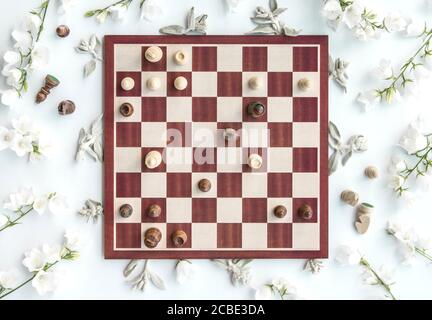 Scène de jeu d'échecs en bois stylisé avec fleurs, puzzle d'échecs, reine sacrifiant, plat, vue d'en haut, style créatif Banque D'Images