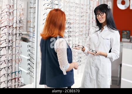 jeune doué agréable opticien consultant client pour acheter des lunettes, vente, rabais, lunettes gratuites. Banque D'Images