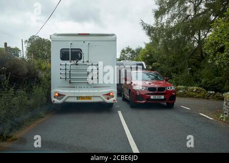 en regardant à travers le pare-brise sur le bloc de route causé par le remorquage d'une voiture caravane de réunion motorhome sur la route étroite près de coniston dans le lac district cumbria engl Banque D'Images