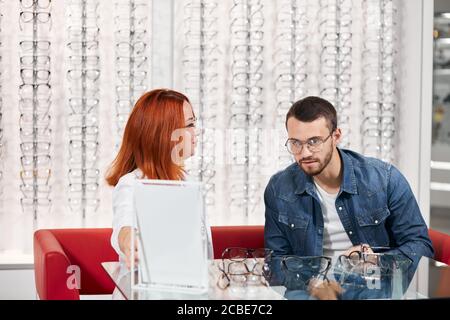 Des soins de santé, les gens, la vue et la vision concept - bon à lunettes opticien montrant à l'homme au magasin d'optique. la photo en gros Banque D'Images