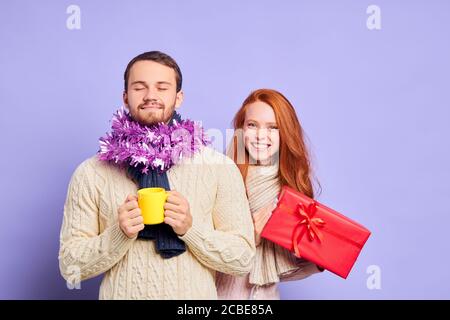 Gaie souriante fille avec de longs cheveux ondulés rouges, vêtue de chandail chaud beige, bande écharpe tricotée à col rond, regardant l'appareil photo avec des expres agréables Banque D'Images
