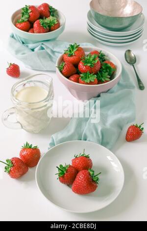 Fraises anglaises fraîches avec un pot de crème épaisse. Couleurs pastel sur fond blanc avec une sensation de lumière et d'air Banque D'Images