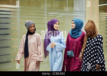 Un groupe de quatre jeunes filles multiethniques islamiques bavardant et se promener ensemble à l'extérieur Banque D'Images