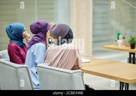 Vue arrière d'un groupe multiracial de femmes musulmanes vêtues de vêtements nationaux élégants étudiant à l'université. Éducation, diversité sociale, amitié. Banque D'Images