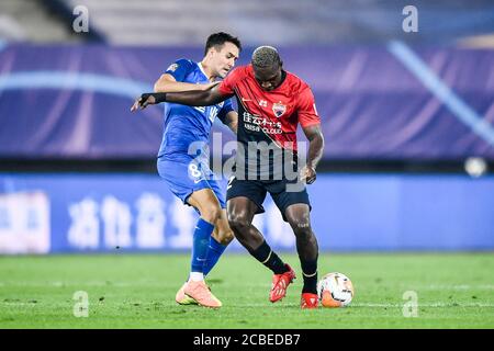 Le joueur de football camerounais John Mary, de Shenzhen F.C., à droite, protège le ballon du joueur de football taïwanais né en anglais Tim Chow, de Henan Jianye F.C., à gauche, lors du quatrième tour du match de la Super League chinoise (CSL) 2020, ville de Dalian, province de Liaoning, dans le nord-est de la Chine, le 10 août 2020. Le F.C. Shenzhen a été battu par le F.C. Henan Jianye avec 1-2. Banque D'Images