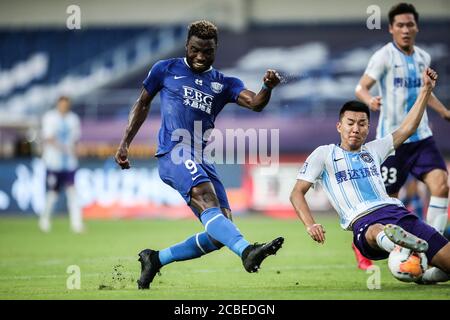 Le joueur de football congolais Oscar Maritu ou Oscar de Shijiazhuang toujours brillant F.C., à gauche, tire lors du quatrième tour du match de la Super League chinoise (CSL) 2020 contre Tianjin TEDA F.C., ville de Suzhou, province de Jiangsu en Chine orientale, 11 août 2020. Le F.C. de Shenzhen a cassé le F.C. de TEDA de Tianjin avec 3-0. Banque D'Images