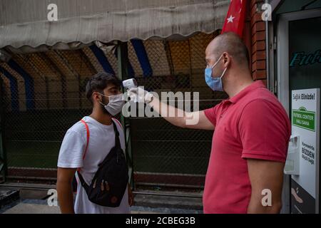 Istanbul, Turquie. 12 août 2020. Un homme obtient sa température corporelle testée avant d'entrer dans un stade de football à Istanbul, Turquie, le 12 août 2020. Les autorités turques ont rouvert mercredi les terrains de football après cinq mois de fermeture dans le contexte de la pandémie COVID-19. Credit: Yasin Akgul/Xinhua/Alay Live News Banque D'Images