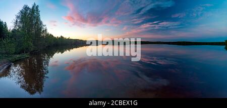 Les nuages sont colorés dans différentes nuances au coucher du soleil sur le lac. Banque D'Images