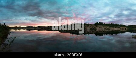 Les nuages sont colorés dans différentes nuances au coucher du soleil sur le lac. Banque D'Images