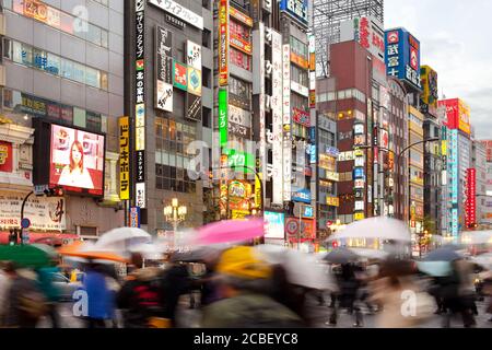 Shinjuku, Tokyo, Japon - Personnes avec parasols sous la pluie dans le quartier animé de Shinjuku. Banque D'Images