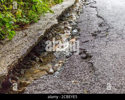 Surface de la route endommagée et évacuée par les eaux pluviales Banque D'Images