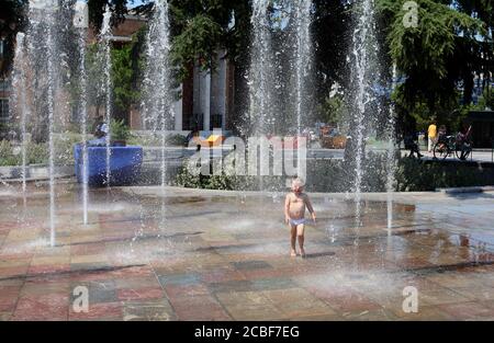 (200813) -- TIRANA, 13 août 2020 (Xinhua) -- UN enfant se rafraîchit dans des fontaines de la place Skanderbeg, au centre de la capitale Tirana, Albanie, le 12 août 2020. L'Albanie a été frappée mercredi par une vague de chaleur avec une température atteignant 39 degrés Celsius. Banque D'Images