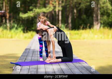 Maman et fille font de l'exercice dans le parc sur un pont en bois le matin d'été. Concept sur un mode de vie sain Banque D'Images