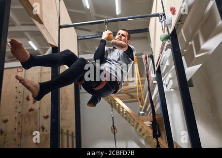 Vue en contre-plongée d'un alpiniste physiquement handicapé se préparant à la compétition internationale de boulonnage, en effectuant des entraînements dynamiques et intensifs, Banque D'Images