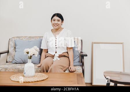 Une femme au foyer en bonne santé et en bonne santé assise dans la salle de séjour chaleureuse souriante, regardant la caméra Banque D'Images