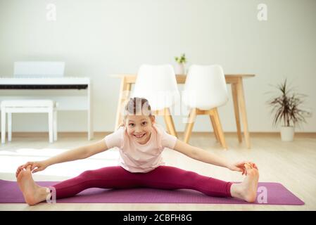 Jolie fille ado heureuse d'enfant ayant le plaisir de faire du yoga extensible exercices à la maison Banque D'Images