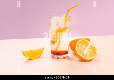 Cocktail d'alcool orange avec tranche de fruits orange sur fond rose et jaune Banque D'Images