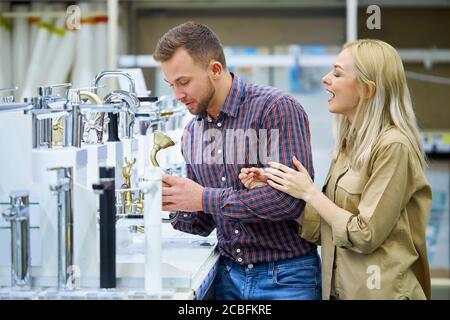 vue latérale sur un jeune couple qui choisit la poignée de la douche pour sa nouvelle baignoire à la maison. faire du shopping ensemble Banque D'Images