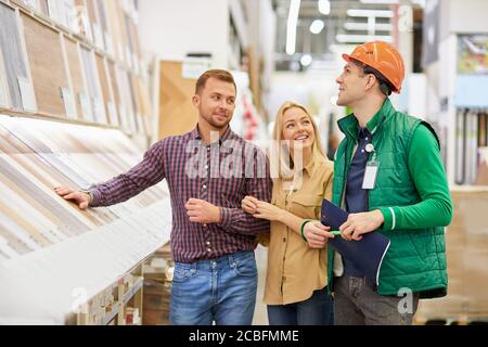 conversation mignonne entre les jeunes clients caucasiens et le travailleur d'entrepôt, ils se tiennent dans le centre de distribution, parlent et sourire Banque D'Images