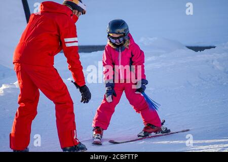 L'Alpe d'Huez, France 02.01.2019 un moniteur de ski professionnel enseigne à un enfant le ski par une journée ensoleillée sur une station de montagne. Vacances actives en famille et enfants. Banque D'Images