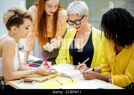 charmante femme mignonne en lunettes et ses collègues collectent, wrrites nouvelles sur le lieu de travail. concept de journalisme Banque D'Images