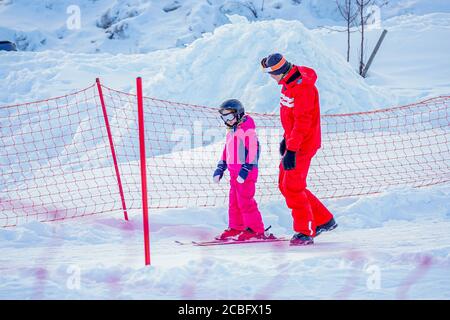 L'Alpe d'Huez, France 02.01.2019 un moniteur de ski professionnel enseigne à un enfant le ski par une journée ensoleillée sur une station de montagne. Vacances actives en famille et enfants. Banque D'Images