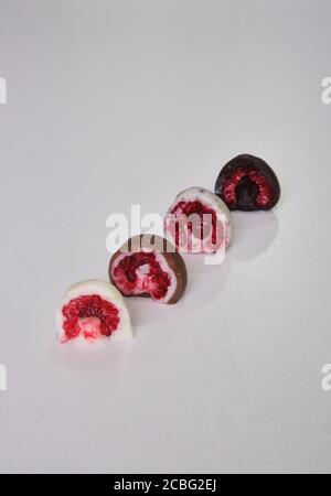 framboises trempées ou recouvertes de chocolat en moule coupé en deux. Différentes saveurs : chocolat blanc, chocolat au lait, chocolat noir et biscuits Banque D'Images