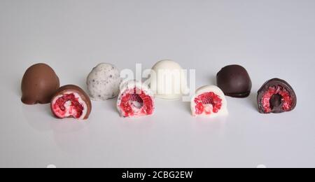 framboises trempées ou recouvertes de chocolat en moule coupé en deux. Différentes saveurs : chocolat blanc, chocolat au lait, chocolat noir et biscuits Banque D'Images