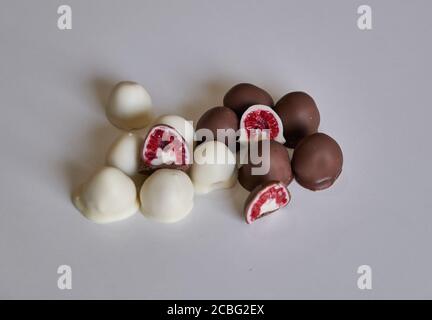 la main de femme choisit et attrapant rouge frais et brillant frais framboises enrobées de chocolat noir et blanc fait maison Banque D'Images