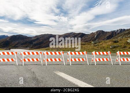 Des barricades en plastique rouge et blanc avec cadre en a se dressent de l'autre côté de la route bloquer le passage - en arrière-plan une vue de les montagnes - illustration 3d Banque D'Images