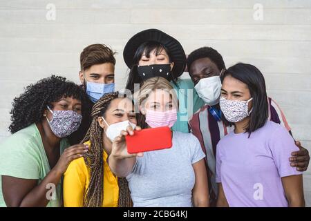 Les jeunes du groupe portant un masque facial prenant le selfie avec mobile Smartphone extérieur - amis du millénaire avec une race et une culture différentes portrait Banque D'Images