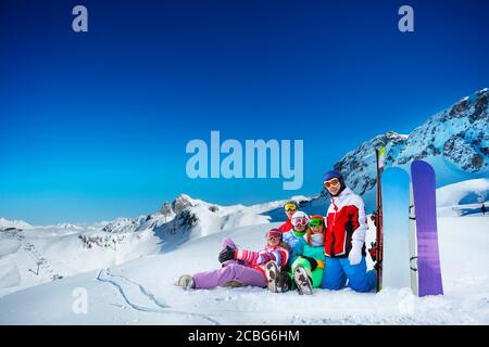Groupe de jeunes adultes heureux couché dans le sourire de neige avec snowboards sur les sommets Banque D'Images