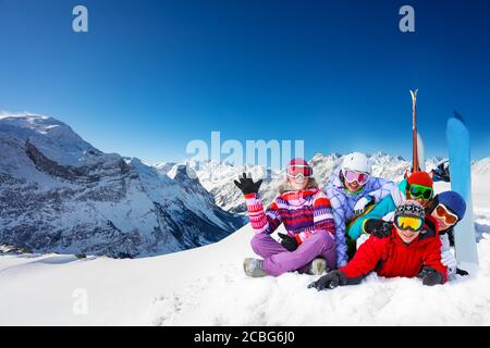 Groupe de jeunes adultes heureux se trouvent dans les mains de la vague de neige avec des snowboards sur les sommets de montagne Banque D'Images