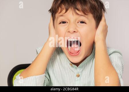 Triste cri autiste portrait de garçon oreilles proches avec les mains, problème d'intégration sensorielle Banque D'Images