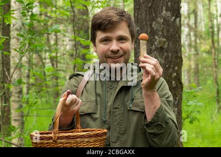 Le vieil homme rassemble des champignons montrant un cep dans le panier. Banque D'Images