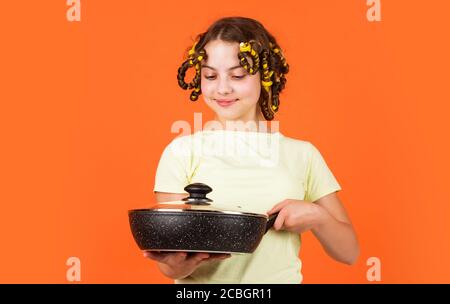 chef confiant. enfant joyeux avec des pillards. ménage de l'enfance. petite femme tient la casserole. cuisine dans la cuisine. concept de ménage. cuisine pour enfants à la maison. bonne enfance. Banque D'Images