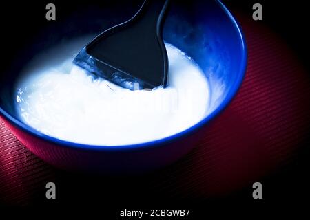 Bol bleu avec mélange pour teindre les cheveux. Palette de colorants à l'intérieur du bol mélangeur Banque D'Images