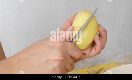 Une femme épluchant les mains de pommes de terre jaunes biologiques avec un couteau près vue vers le haut Banque D'Images