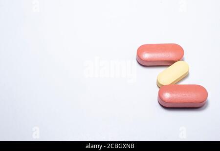 Deux capsules brunes et une capsule blanchâtre sur fond blanc. Avec espace à écrire. Banque D'Images