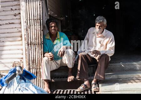 Bhopal, Madhya Pradesh, Inde - Mars 2019 : deux hommes indiens assis près du bord de la route et fuyant des cigarettes. Banque D'Images