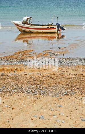 Cromer, Norfolk et un bateau de pêche de jour a laissé coincé sur la plage à marée basse. Banque D'Images