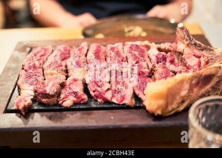 Close-up d'un steak de côtes de bœuf à point tranché sur une dalle de pierre crépitante dans un restaurant à Alicante, Espagne Banque D'Images