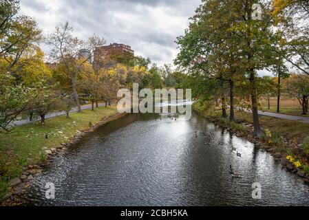 Canal bordé d'arbres et de chemins pavés dans un public garez-vous sous les nuages de ststom un jour d'automne Banque D'Images