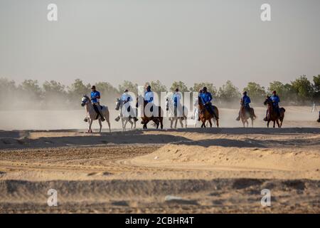 Groupe de jeunes cavaliers pratiquant sur un stock de désert photo Banque D'Images